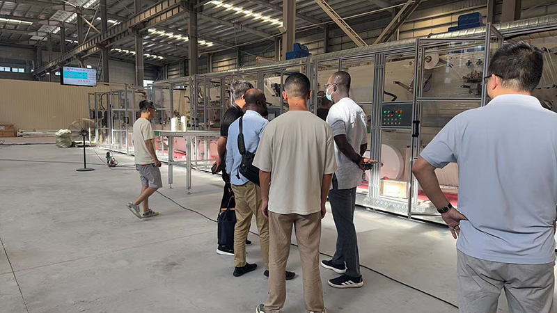 Clientes de Bangladesh visitam fábrica da RX para inspeção de máquina de absorventes higiênicos.